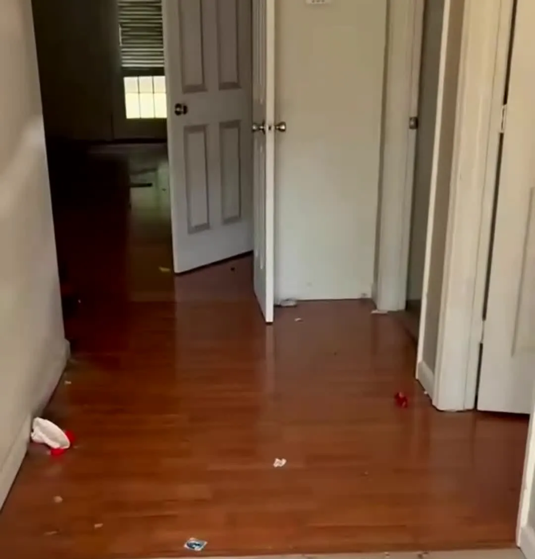 Empty hallway before a move-out clean with trash left on the floor